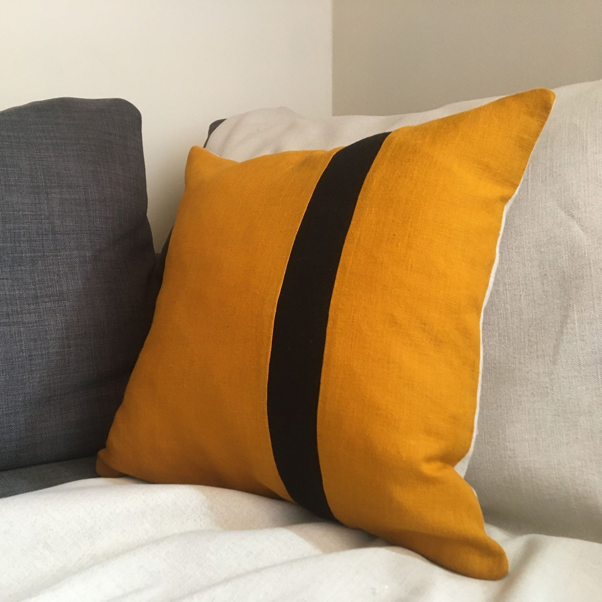 Bee cushion on grey sofa with black stripe